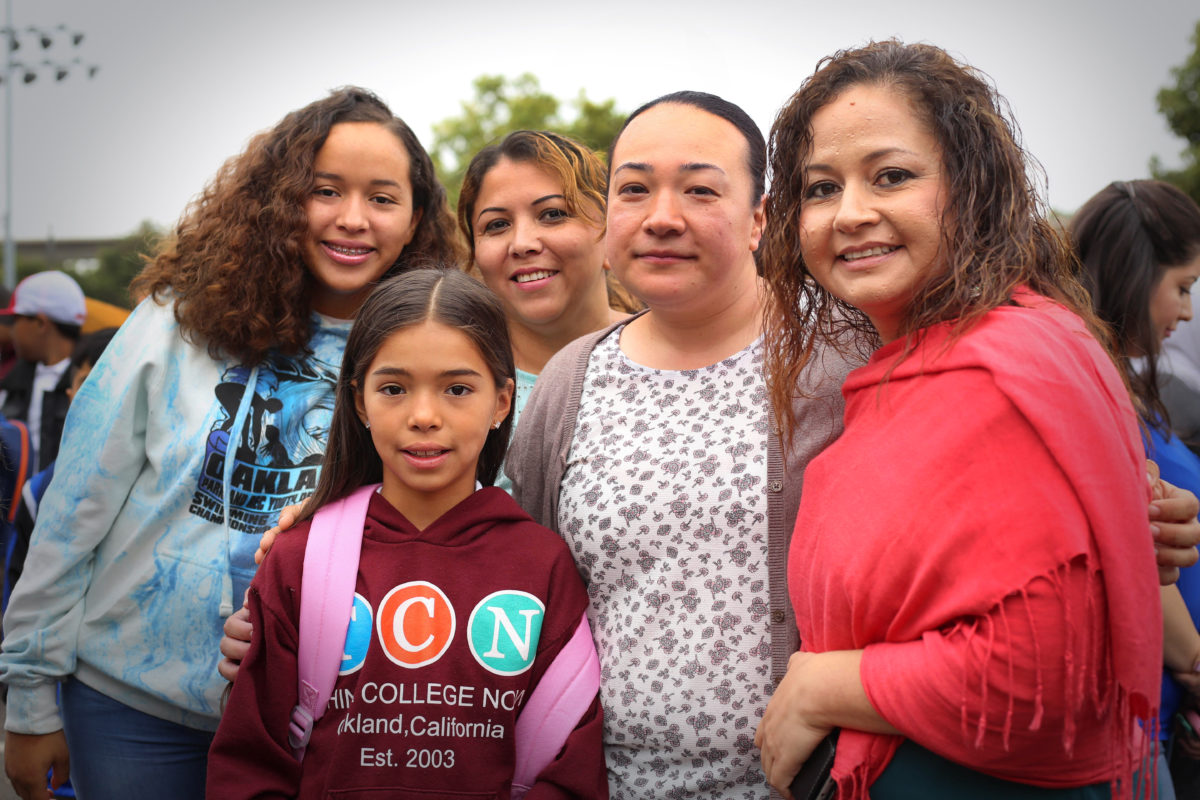 Photo of Raquel Jimenez of Oakland Unified School District welcoming a family on the opening day of school in August 2018.